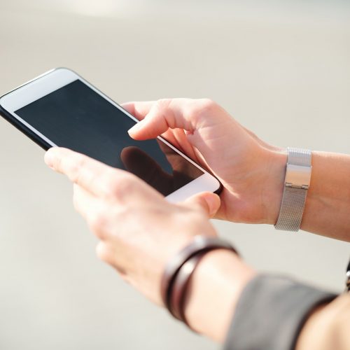 Hands of young elegant businesswoman with smartphone scrolling through contacts